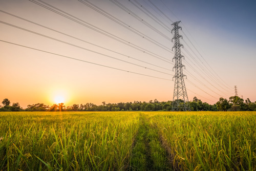 Hochspannungsmast mit elektrischen Freileitungen vor einem Sonnenuntergang