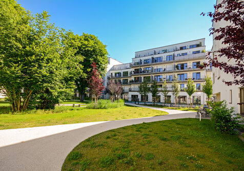 Eine Wohnanlage mit kleinem Park bei Sonnenschein und blauem Himmel