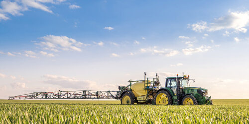 Landwirtschaftsgerät auf einem grünen Feld mit blauem Himmel.