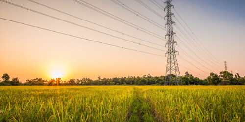 Hochspannungsmast mit elektrischen Freileitungen vor einem Sonnenuntergang