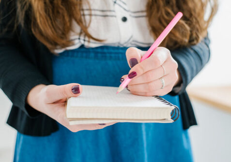 Frau mit Notizblock und Bleistift in der Hand